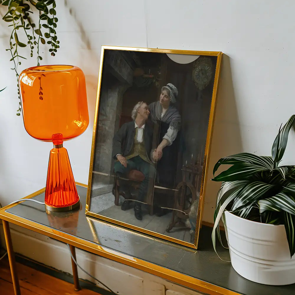 Framed painting of a couple holding hands, displayed on a contemporary console table alongside an orange lamp and a potted plant.