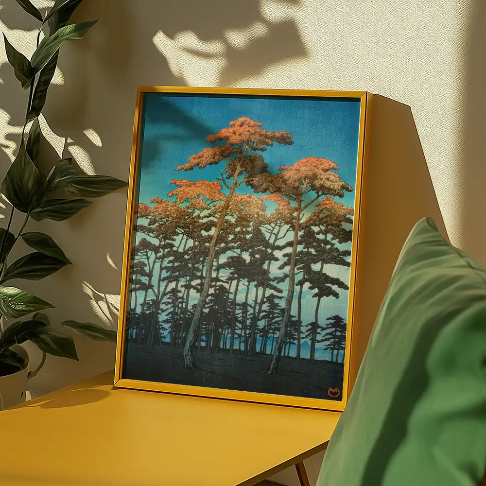 A framed painting of tall trees against a blue sky with orange foliage, displayed on a yellow table, surrounded by indoor plants.