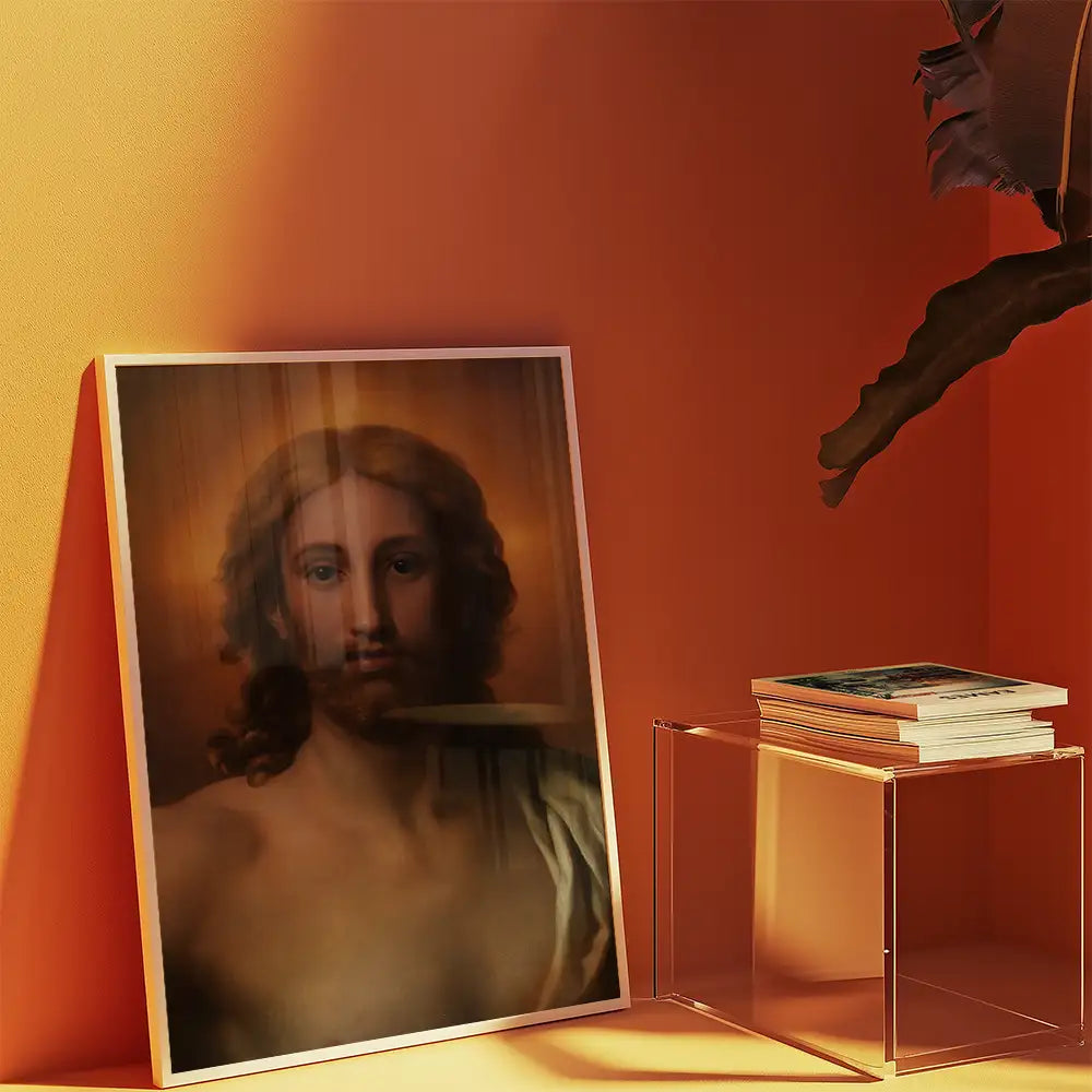 Framed painting of a serene figure with long hair and a beard, displayed against an orange wall, alongside a stack of books on a clear acrylic table.