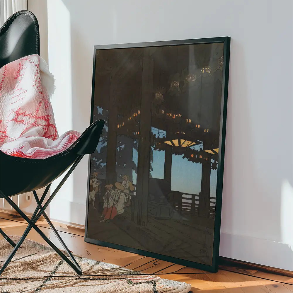 Framed painting leaning against a wall, depicting a tranquil outdoor scene with lanterns and people, next to a black chair and patterned rug.