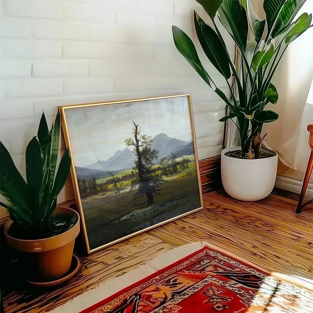 A framed landscape painting featuring mountains and a tree, displayed in a bright room with indoor plants and wooden flooring.