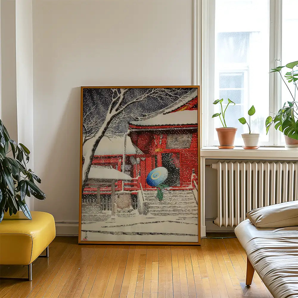 Painting of a snowy landscape featuring a red building and traditional umbrella, displayed in a cozy living room setting with indoor plants and modern furniture.