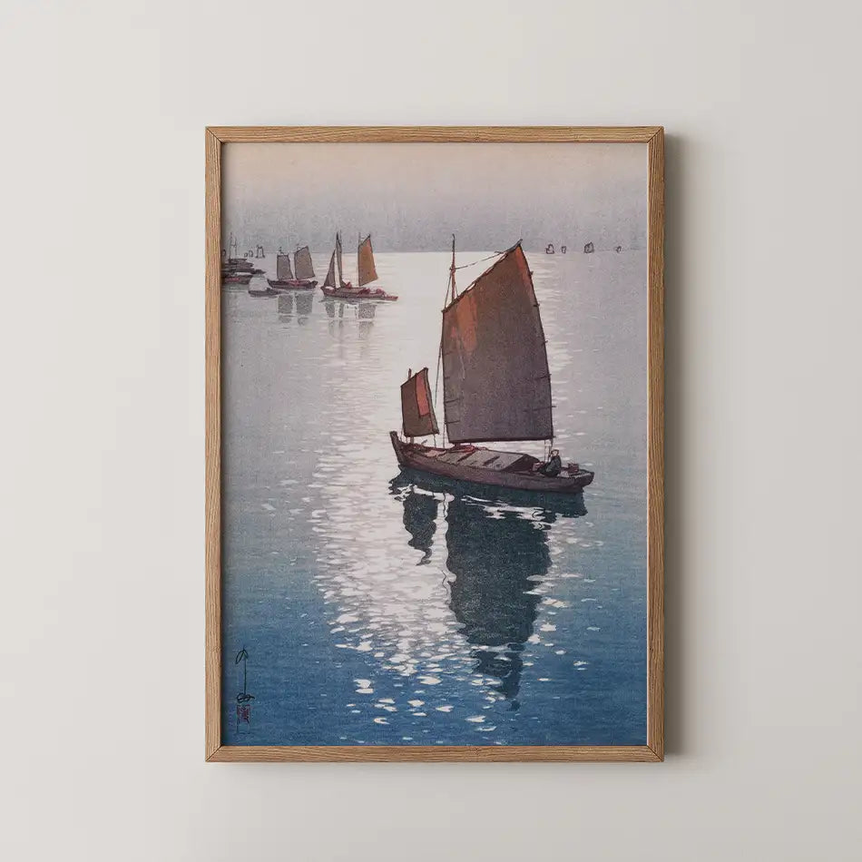 Framed painting of boats with red sails on a tranquil water surface reflecting light, featuring a serene coastal landscape.