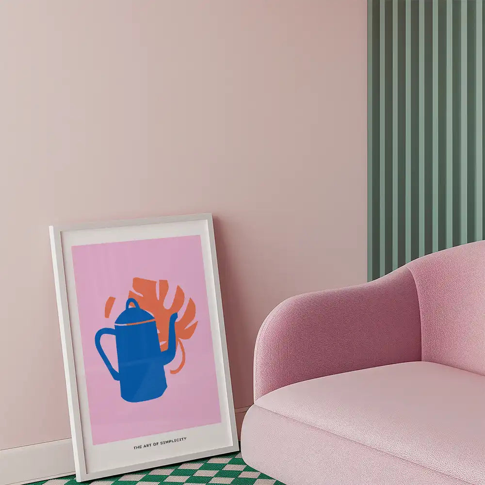 Colorful modern poster of a blue kettle with a pink background and tropical leaf design, framed and displayed in a chic interior setting.