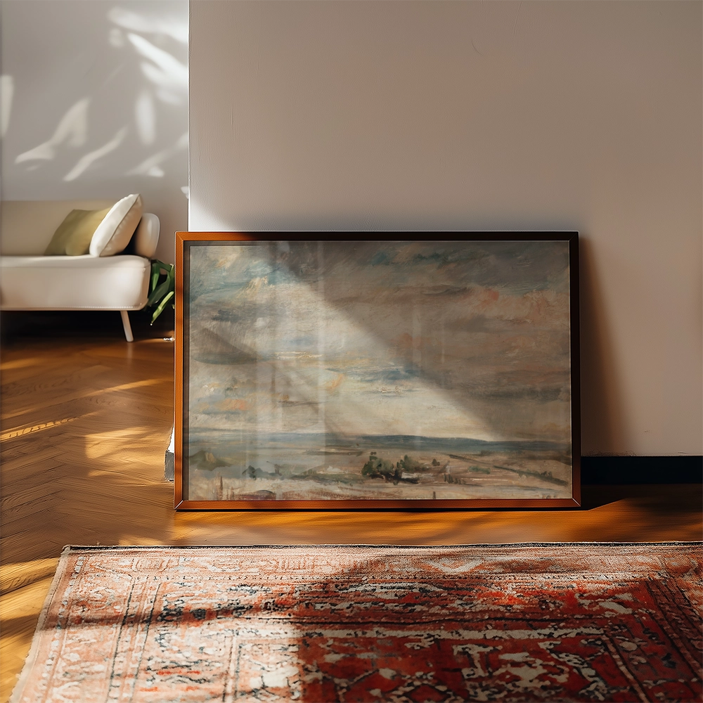 Framed landscape painting leaning against a wall in a sunlit room with hardwood floors and a patterned rug.