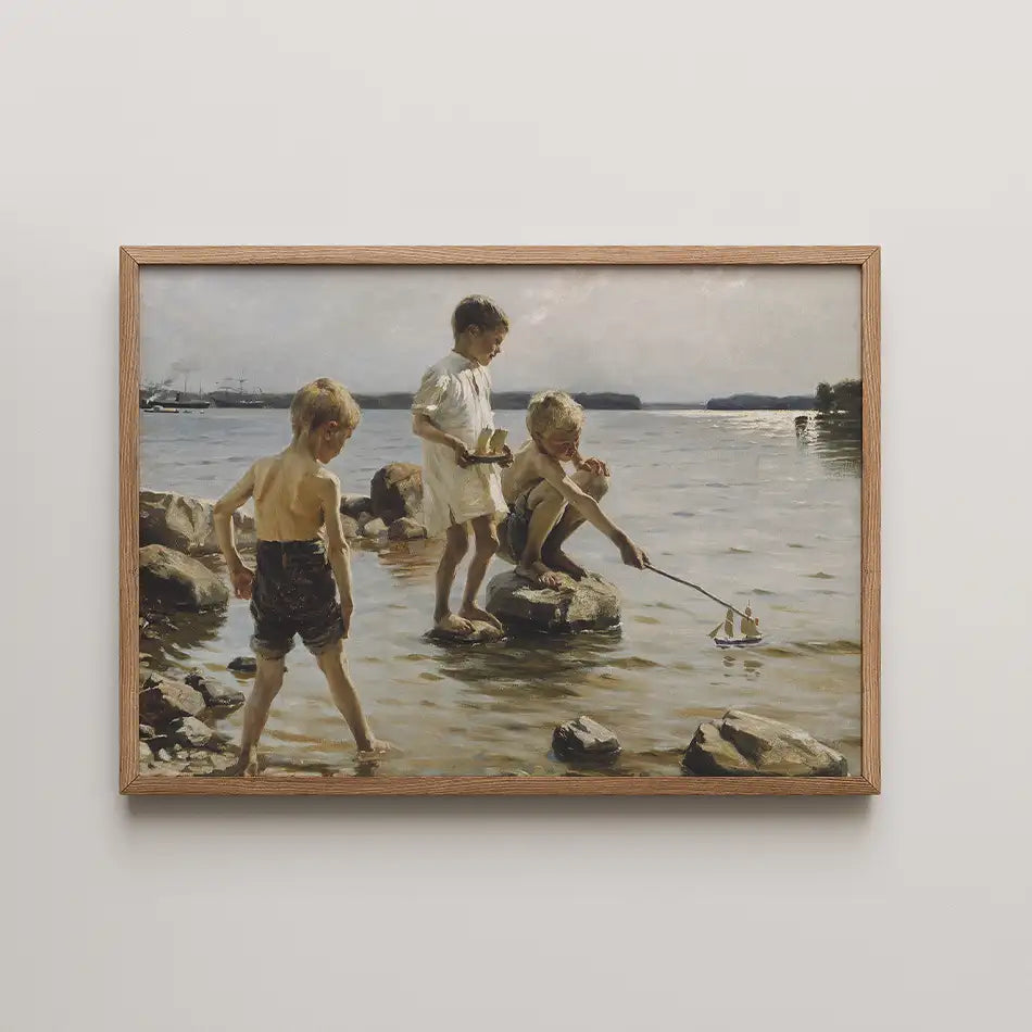 Painting of three children playing by the water, one boy launching a toy sailboat and two others observing, framed in wood.