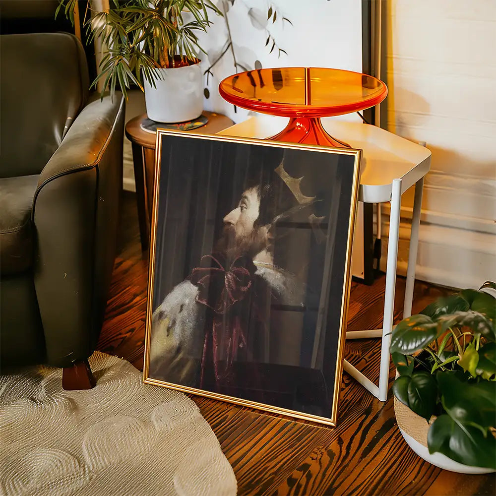 Framed painting of a regal figure with a crown and ornate clothing, leaning against a couch in a stylish interior setting.