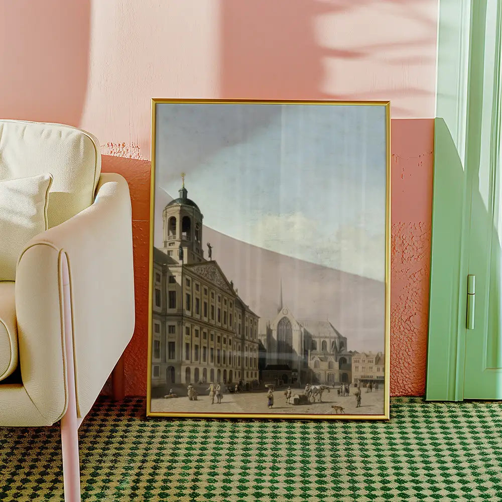 Framed historical painting of a building facade displayed in a bright living room setting with a cream-colored armchair and patterned rug.