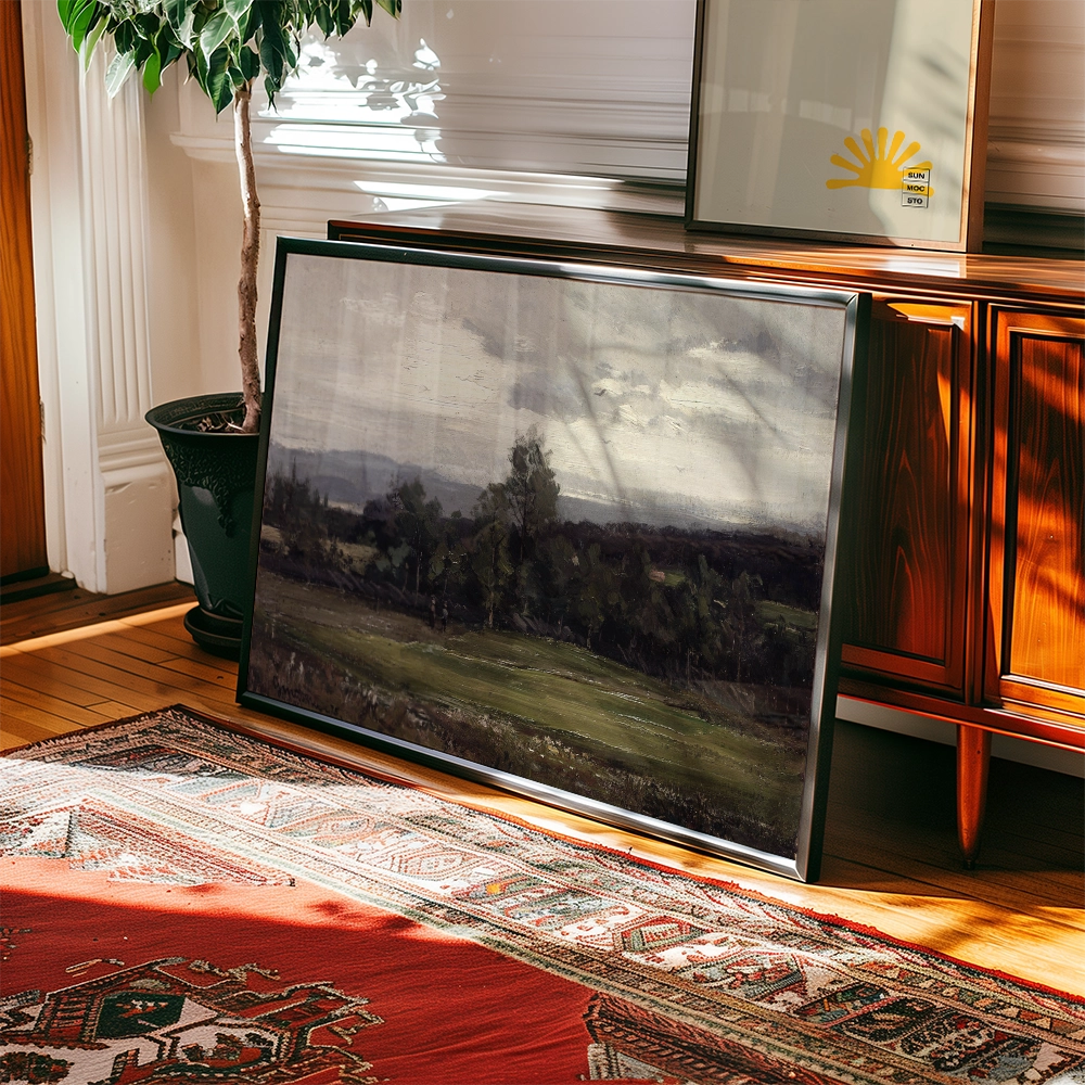Framed landscape painting leaning against a wooden surface with a potted plant and decorative rug in the background.