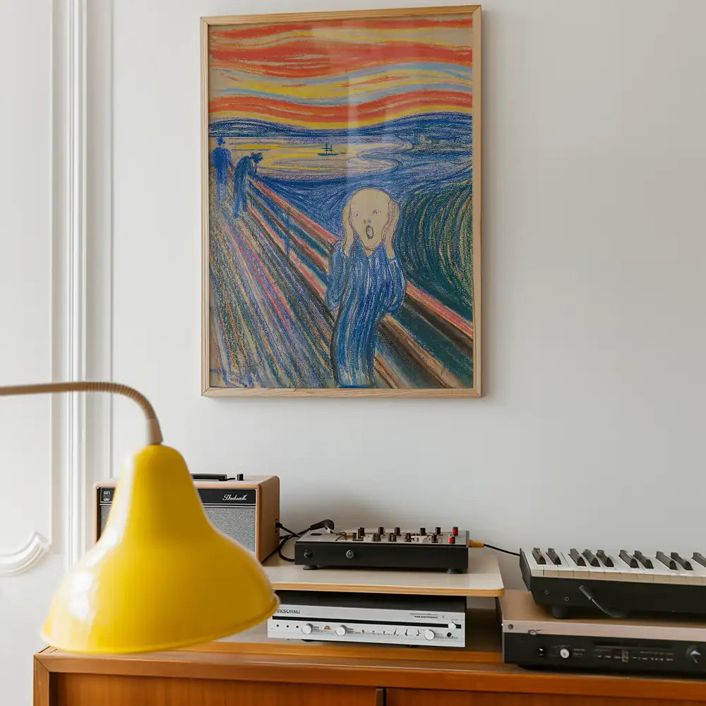 Framed painting of an abstract figure with a screaming expression against a vibrant sunset background, displayed on a white wall above a wooden side table with vintage audio equipment and a yellow lamp.