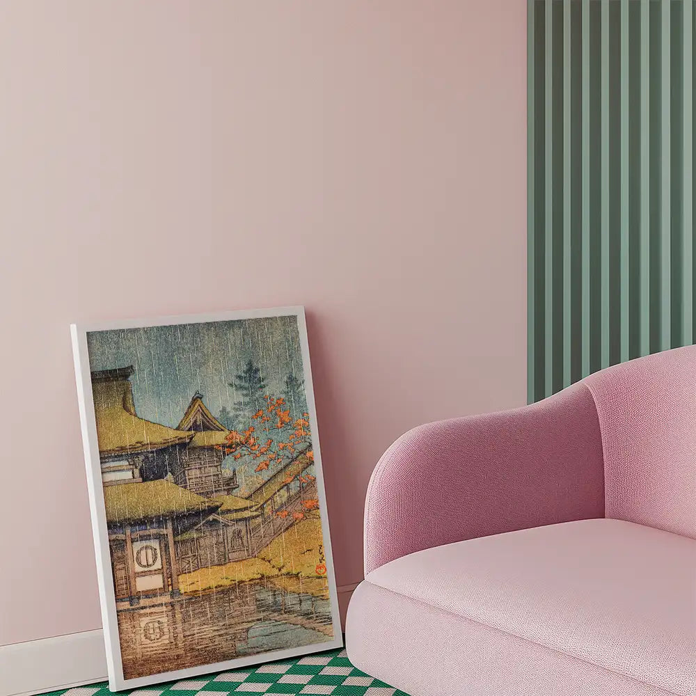 Framed painting of a traditional Japanese landscape with a house and autumn trees displayed next to a pink sofa in a modern room.