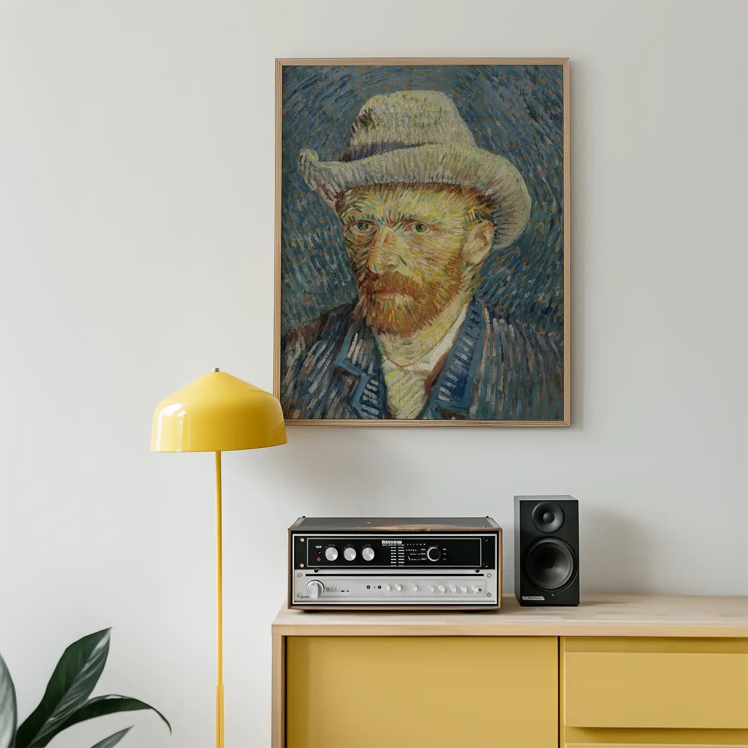 Portrait painting of a bearded man wearing a hat, framed and displayed on a wall above a yellow lamp and vintage audio equipment.