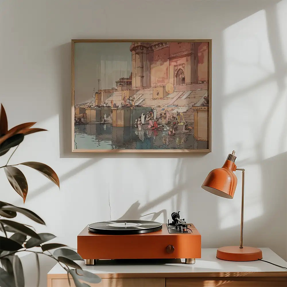 A framed painting of a bustling riverside scene with people gathered, presented above an orange turntable and lamp in a cozy room setting.