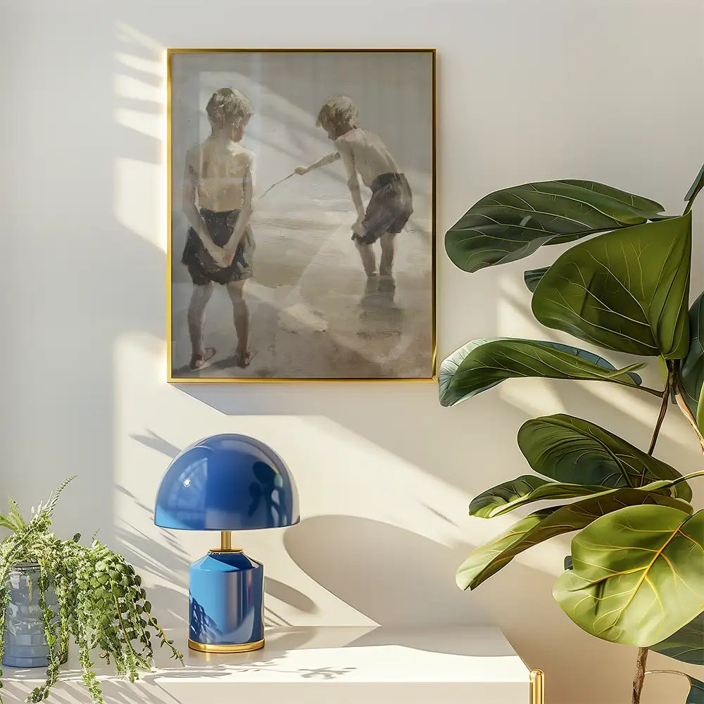 Framed painting of two children playing by the water, displayed on a wall with a blue lamp and green plants in a bright room.