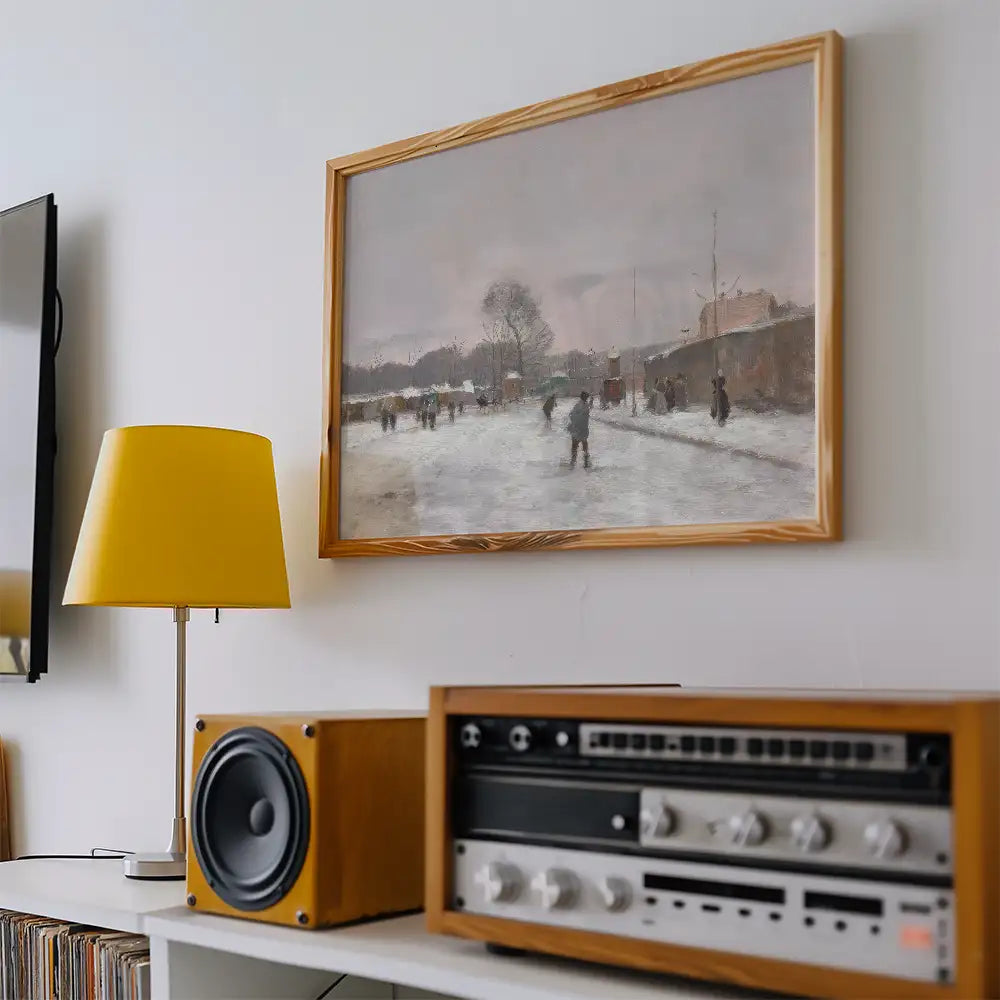 Framed painting of a winter scene with people walking in the snow, displayed on a wall next to a yellow lamp and vintage audio equipment.