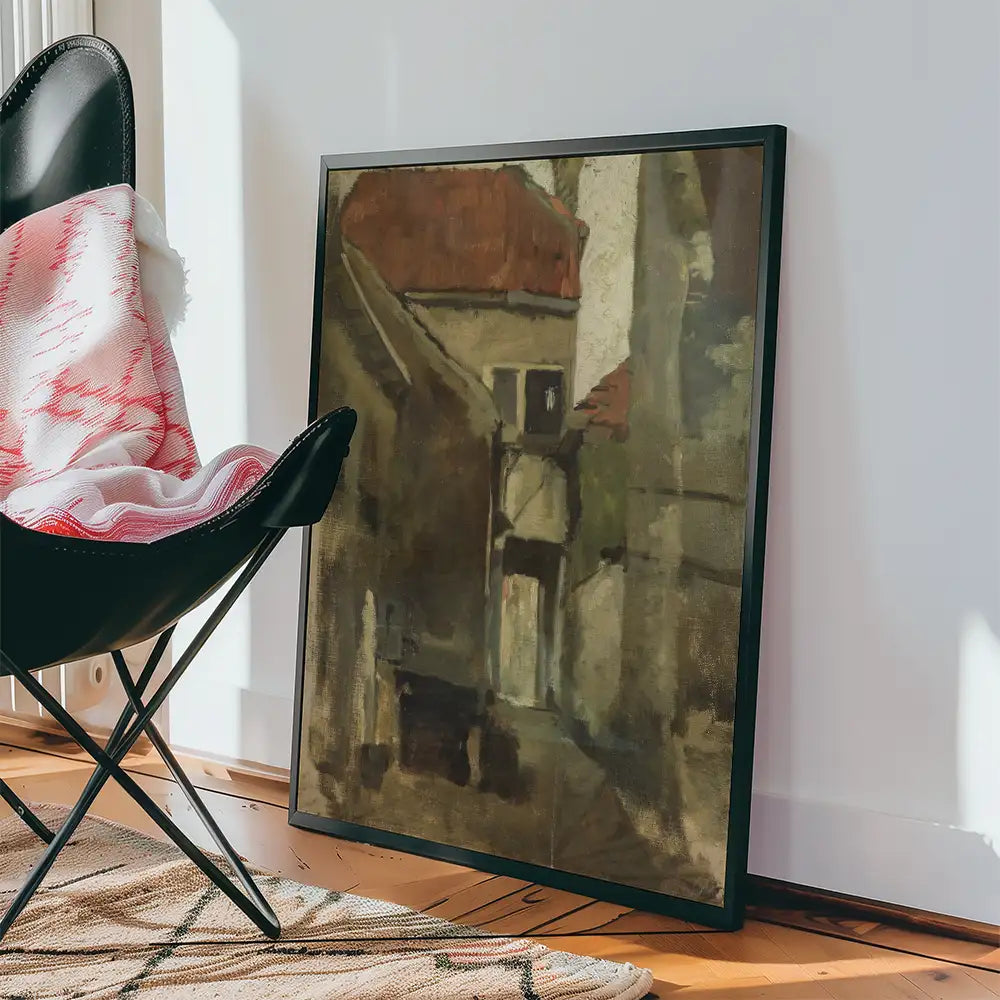 Framed abstract painting of a muted street scene leaning against a chair in a cozy interior setting.