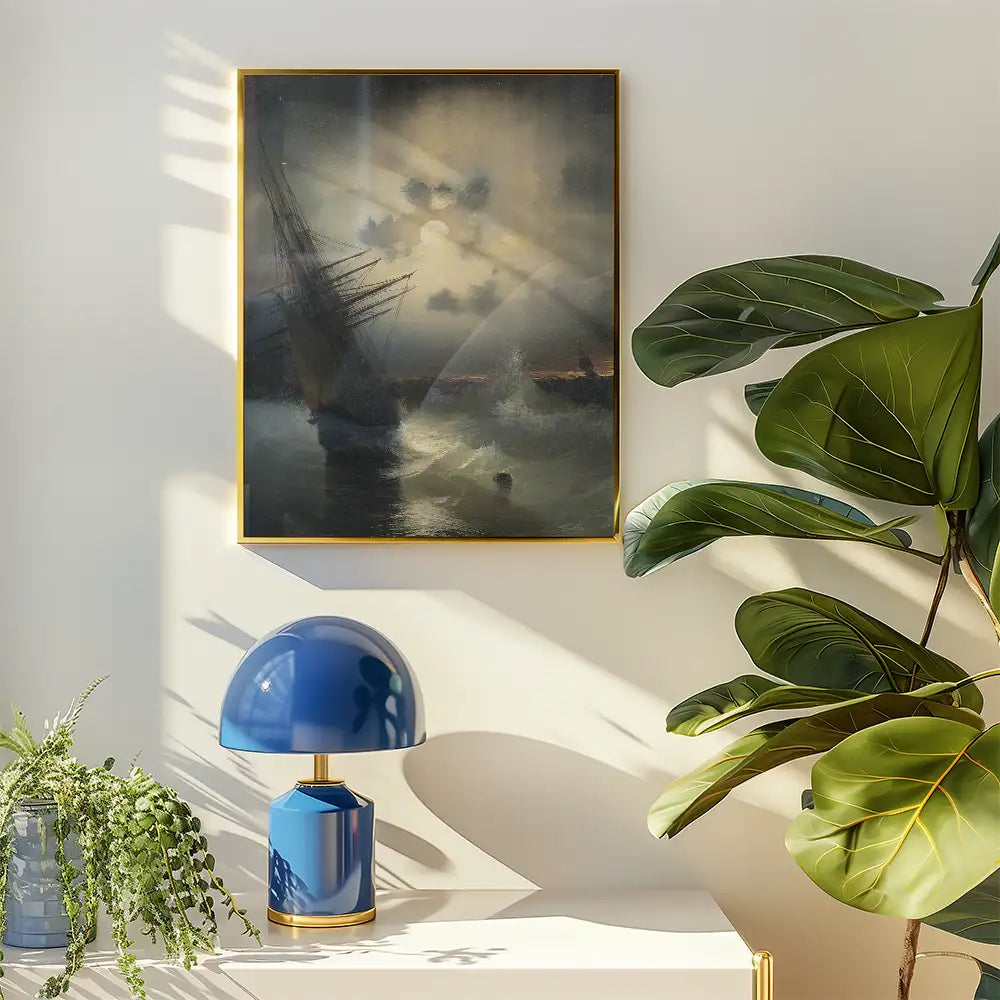 Painting of a ship at sea displayed in a gold frame, accompanied by a blue table lamp and potted plant, on a light-colored wall.