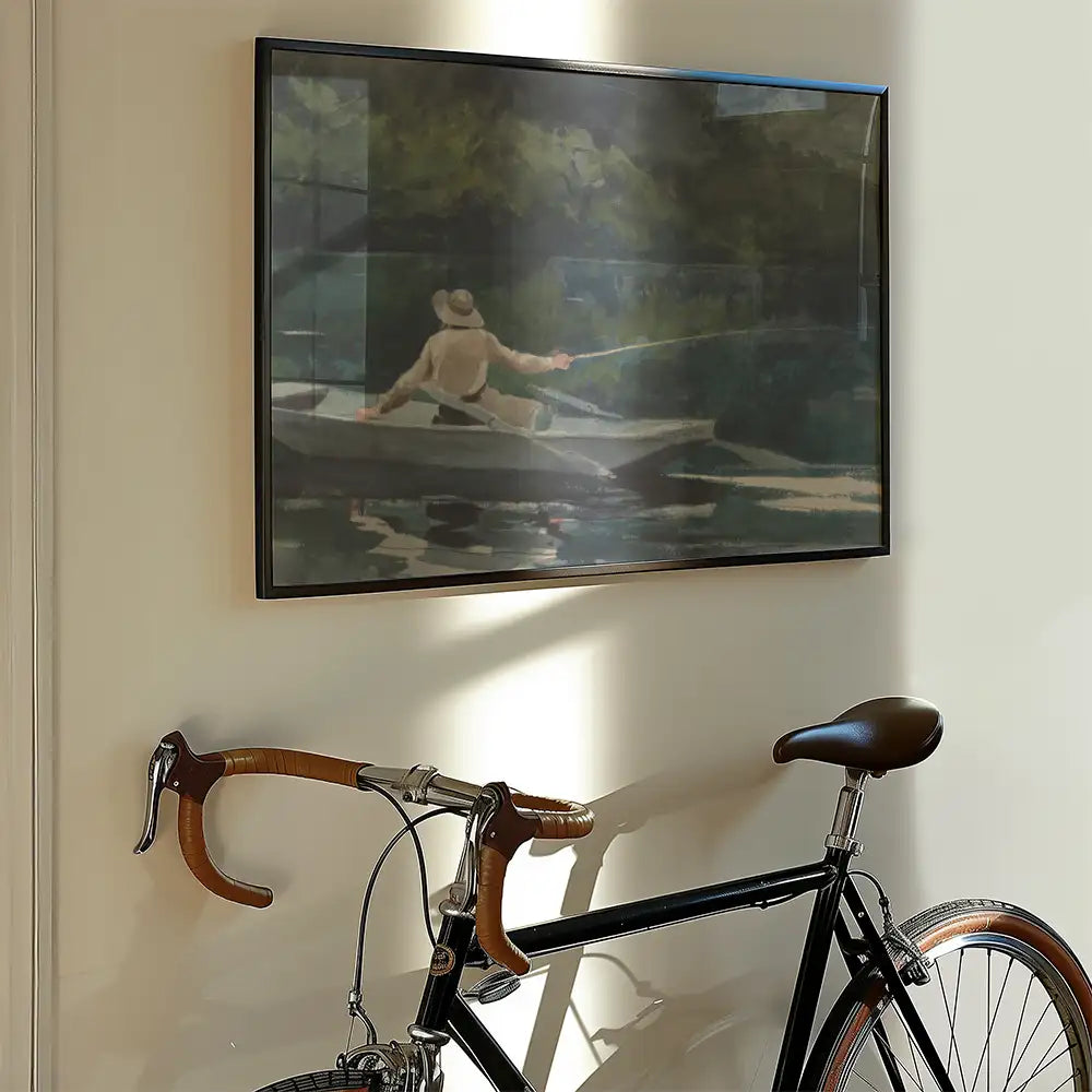 Framed painting of a man fishing from a boat, displayed on a wall next to a vintage bicycle.