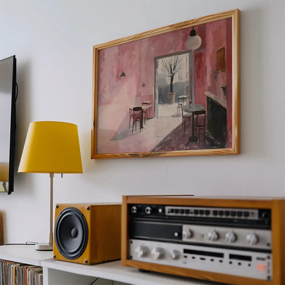 Modern reprint of a famous painting featuring a pink interior with empty chairs and a tree outside, displayed above a vintage audio setup and yellow lamp.