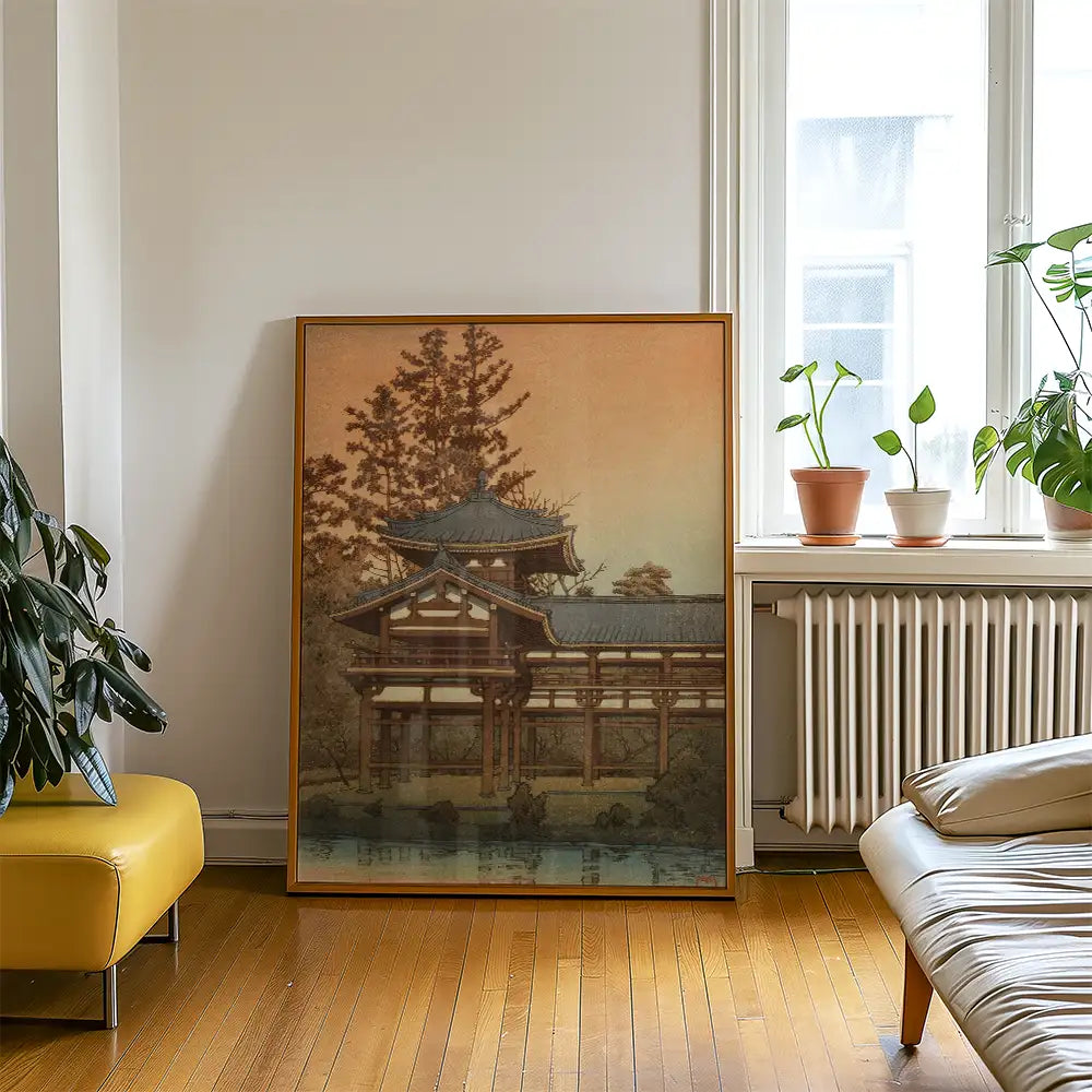 Large framed painting of an East Asian architectural structure surrounded by trees, displayed in a bright living room with indoor plants and yellow furniture.
