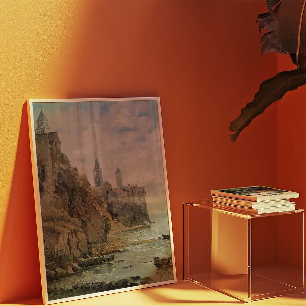 A framed painting of a castle on a cliff by the sea, displayed against an orange wall with a stack of books nearby.