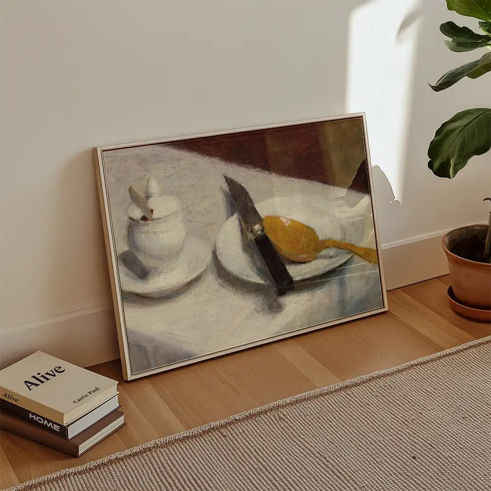 Painting of a table setting featuring a knife, a yellow spoon, and a cup on white plates, leaning against a wall with a potted plant nearby.