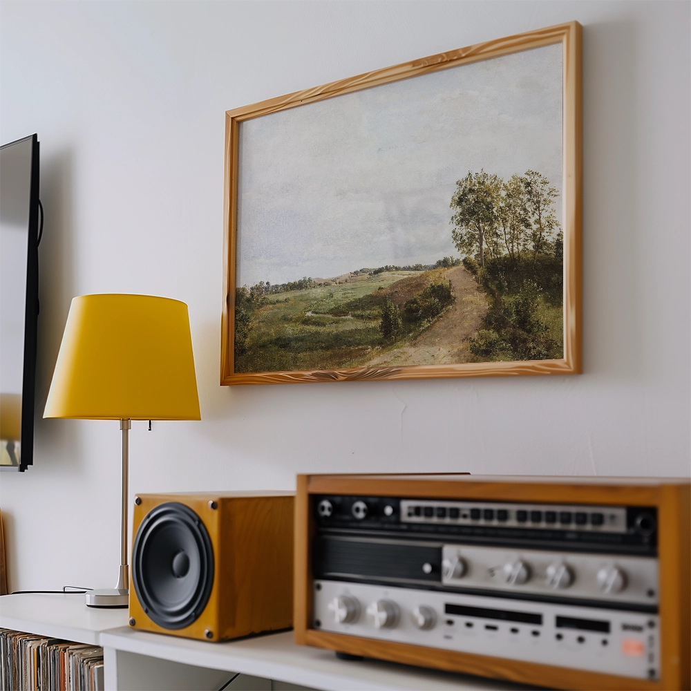A vintage landscape painting in a wooden frame hanging on a wall, with a yellow lamp and a vintage audio system in the foreground.