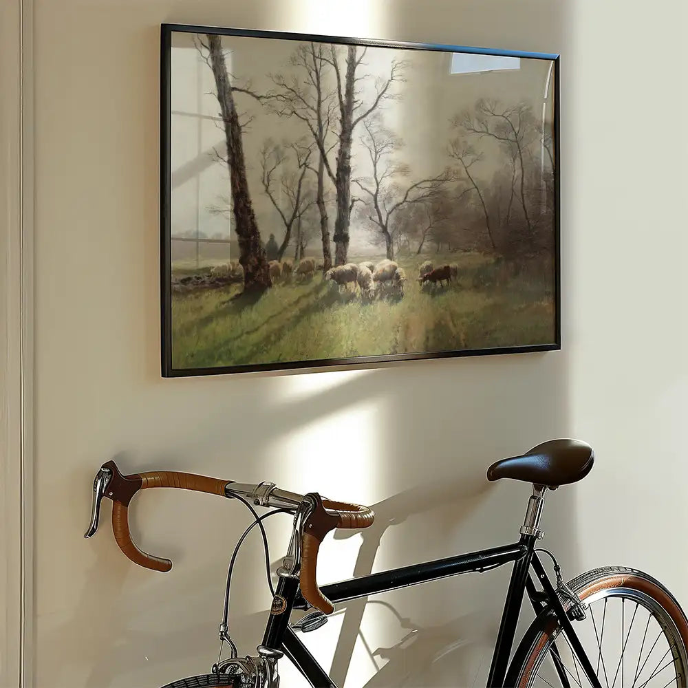 Framed painting of a pastoral scene with sheep grazing in a field, hanging on a wall next to a vintage bicycle.