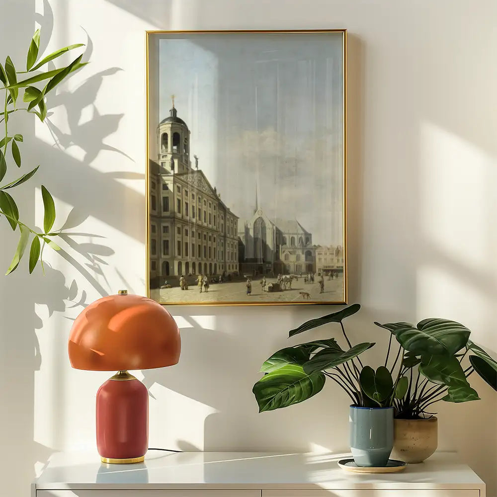 Framed painting of a historical cityscape featuring a square with buildings and a church, accompanied by a decorative lamp and indoor plants.