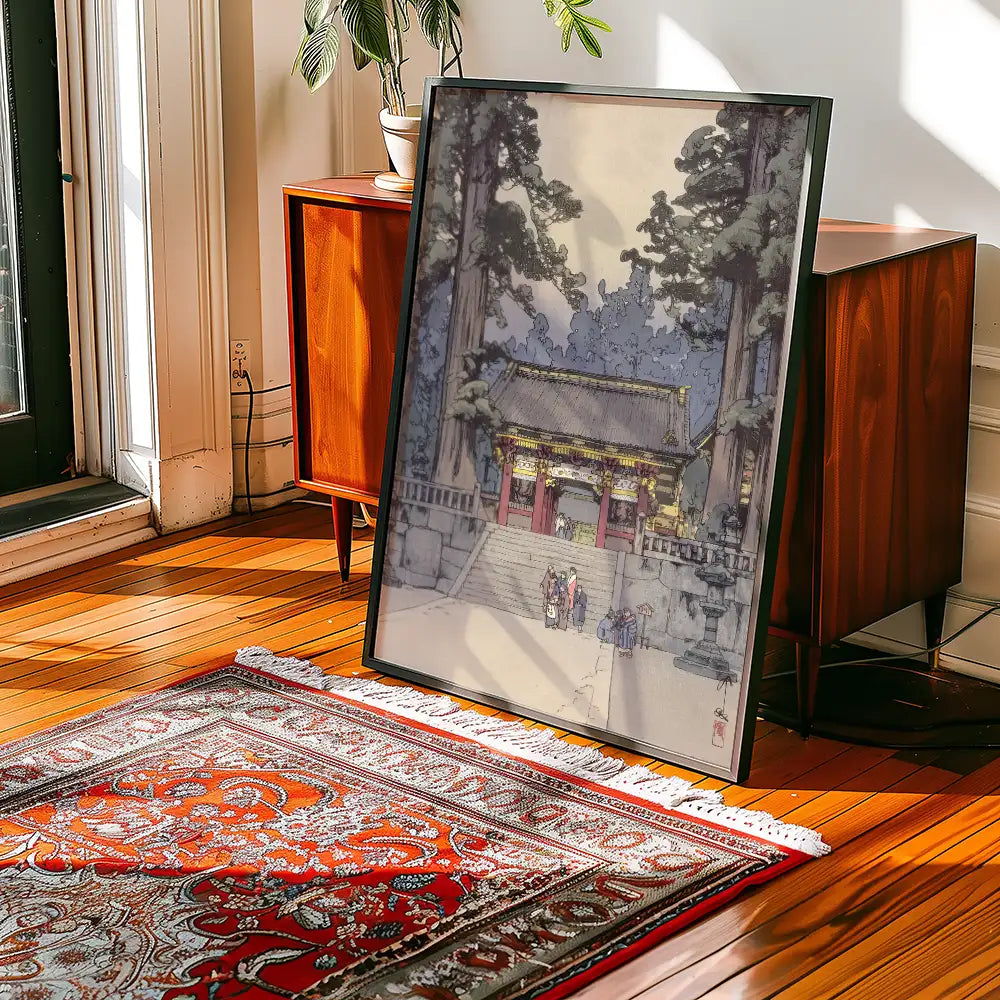 Framed painting depicting a traditional temple entrance surrounded by tall trees, placed in a sunlit room with wooden floors and a patterned rug.