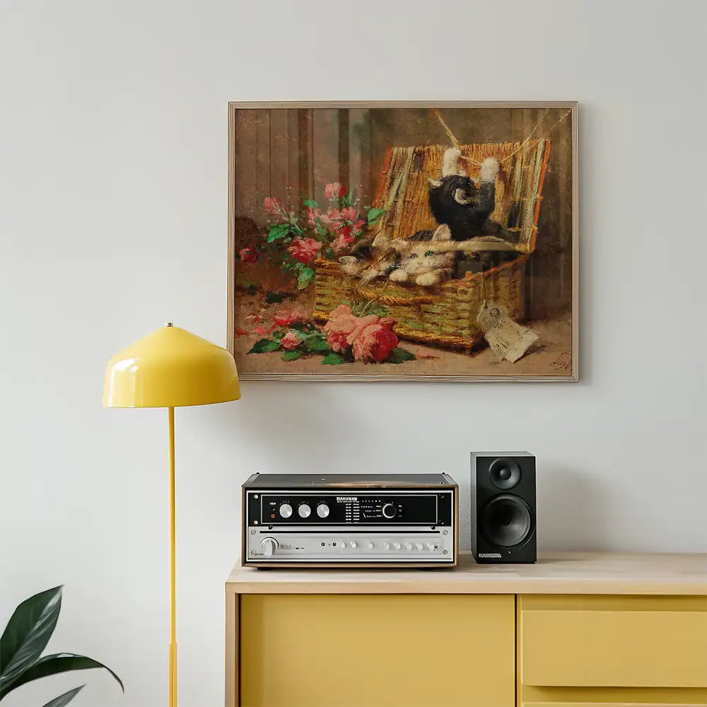 Framed painting of two playful kittens in a wicker basket surrounded by colorful flowers, displayed above a vintage stereo on a yellow cabinet.