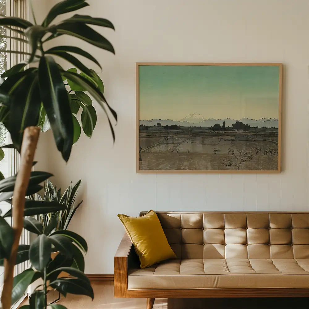 Framed landscape painting hanging above a leather sofa with a yellow cushion in a modern living room setting.