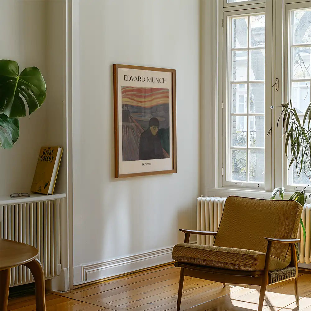 Framed poster of Edvard Munch's "Despair" hanging on a white wall next to a brown armchair and a potted plant in a cozy living room setting.