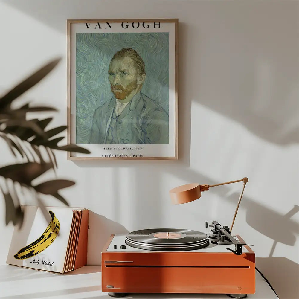 Vincent van Gogh self-portrait painting framed on a wall above a vintage record player with an orange finish and an Andy Warhol banana art piece nearby