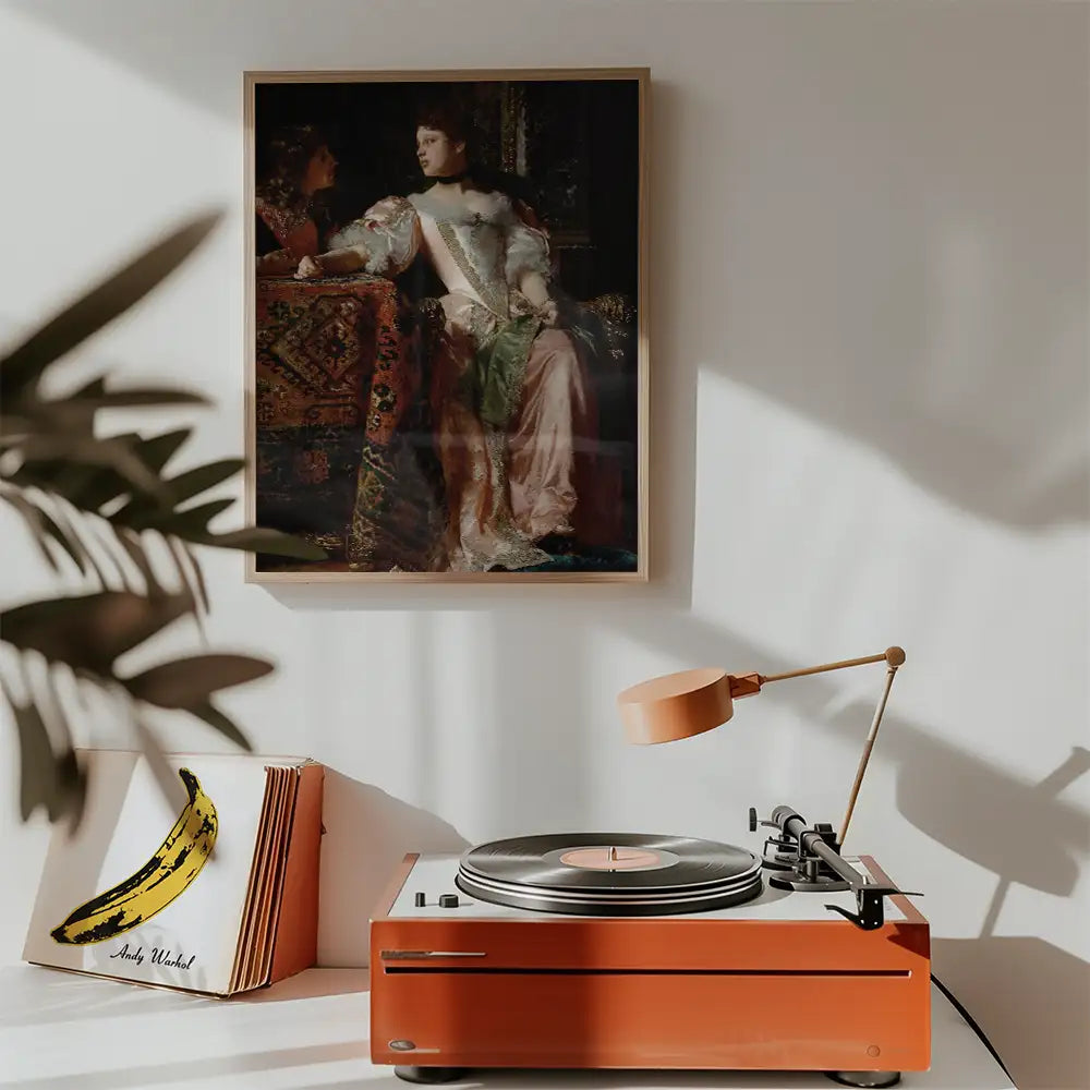 Painting of two women in period clothing hanging above a vintage record player with a banana art print nearby.