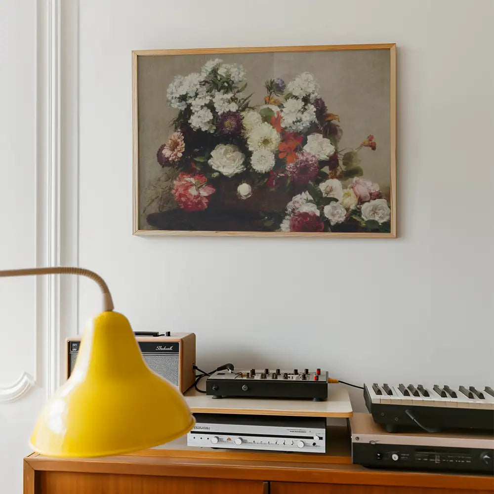 A framed painting of a colorful floral arrangement hanging on a wall above a wooden sideboard with modern decor elements.