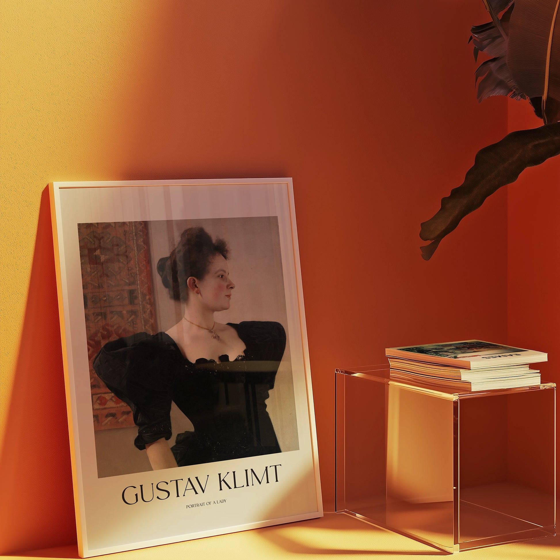 Portrait of a lady by Gustav Klimt in a framed poster displayed against an orange wall with a clear acrylic side table holding books.