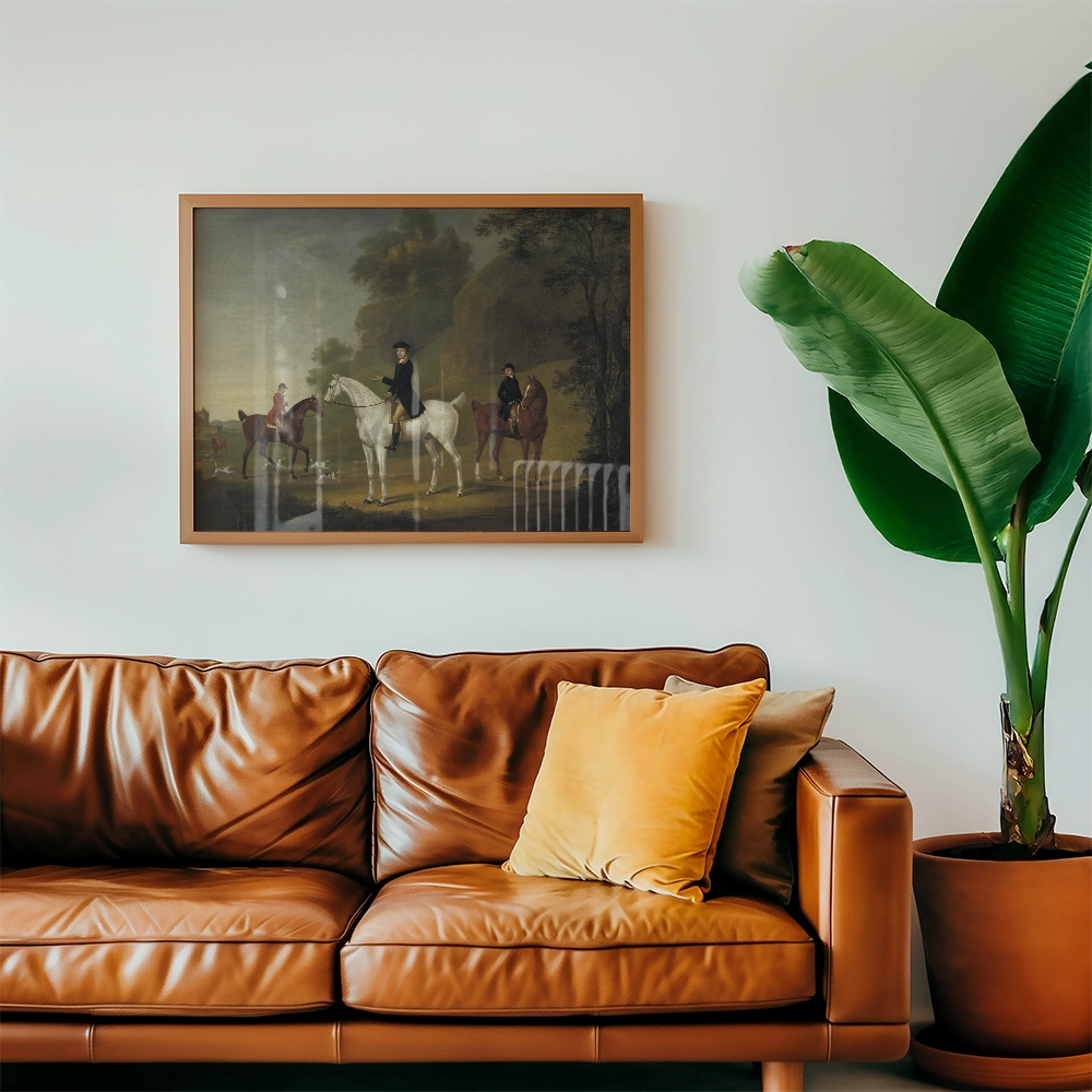 Painting of a horse and riders framed on a wall above a brown leather couch with a yellow decorative pillow and a large green plant.