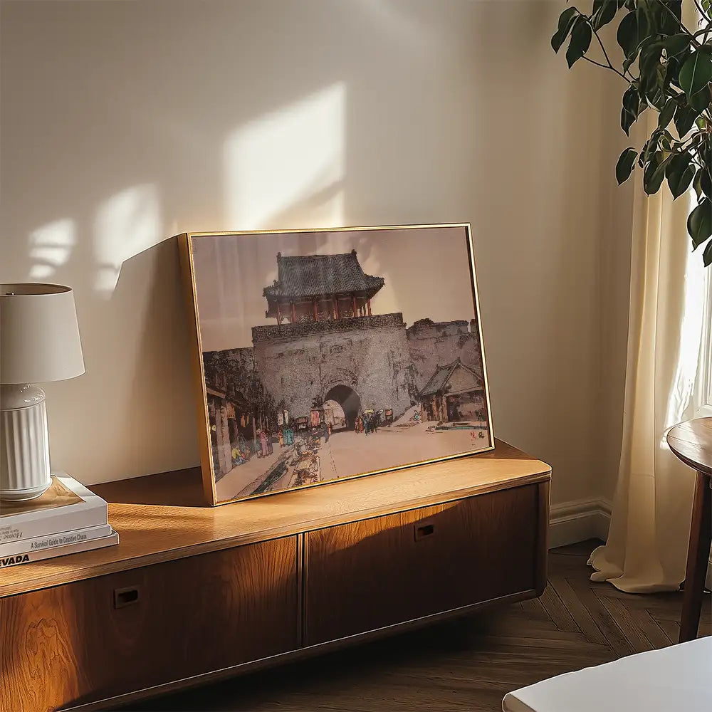Framed painting of an ancient city gate displayed on a wooden console table in a sunlit room