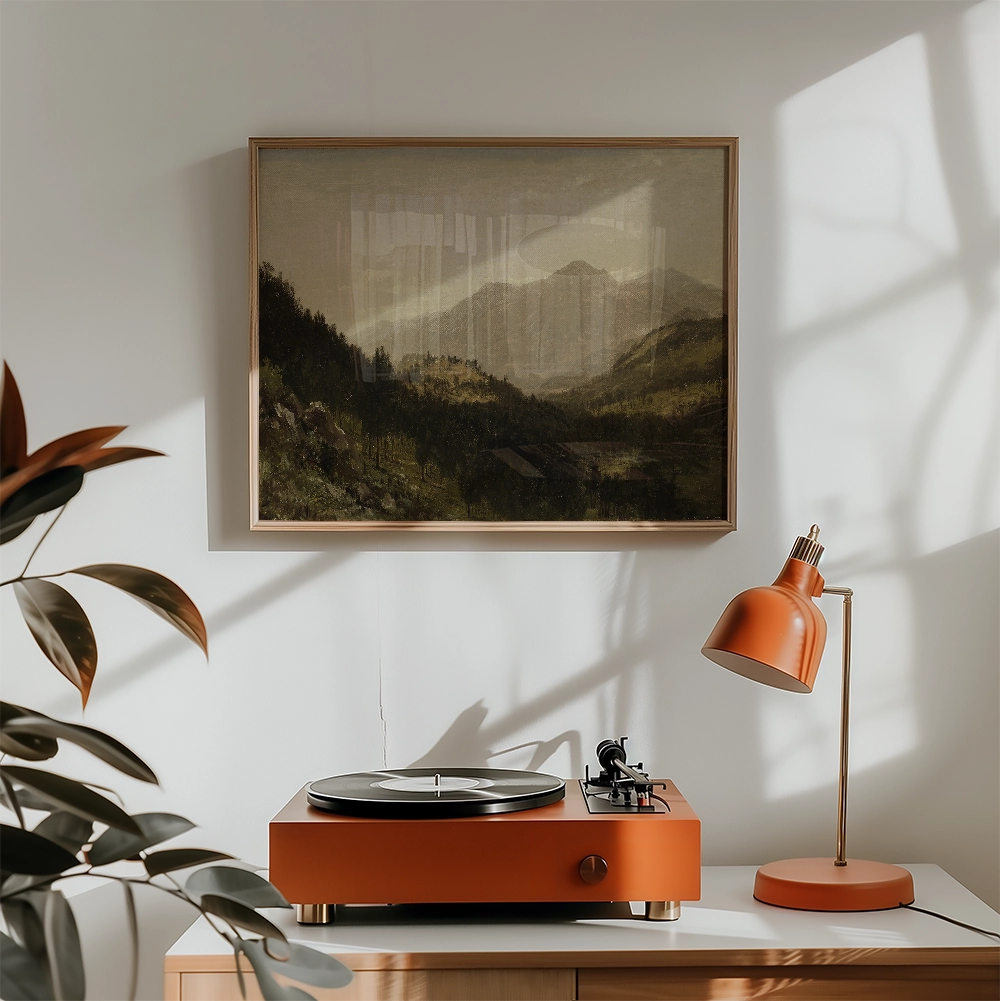 Framed painting of a mountainous landscape hung on a wall above an orange record player and a matching lamp in a modern interior setting.