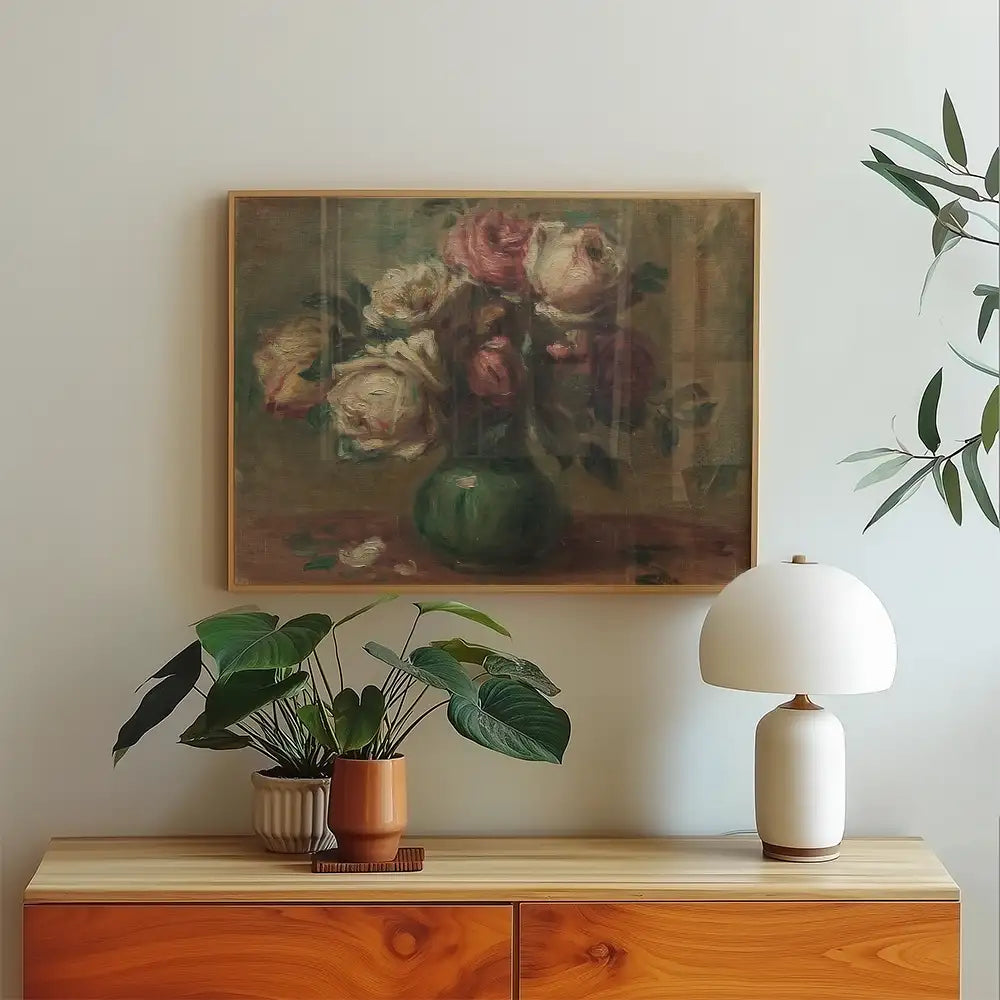 Painting of a bouquet of roses in a green vase hung on a wall above a wooden console table with plants and a lamp.