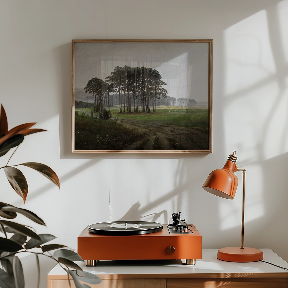Framed painting of a serene landscape with a group of trees, displayed above a record player and orange desk lamp in a bright interior setting.