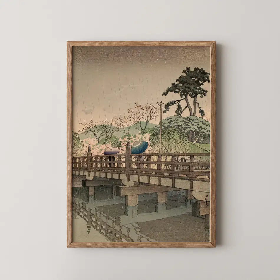 Framed painting of a bridge with people holding umbrellas in a rainy landscape setting.