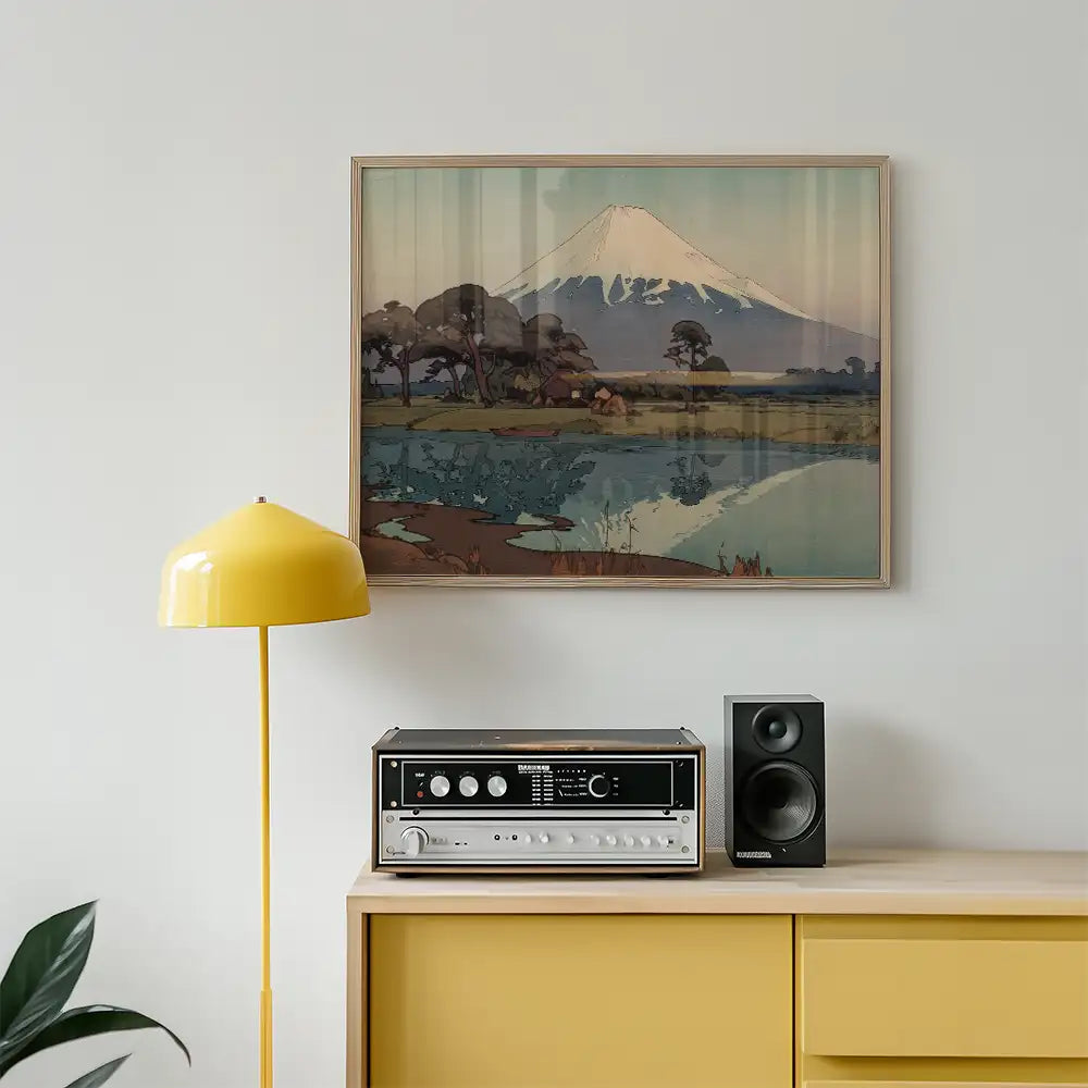 Framed painting of a mountain reflection in a lake, displayed above a yellow lamp and retro stereo, set in a modern interior.
