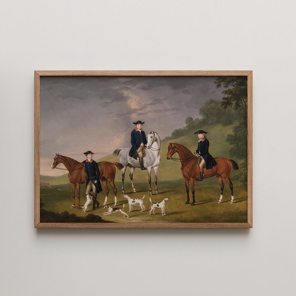 Painting of three riders on horseback in a pastoral setting, accompanied by dogs, framed in natural wood.