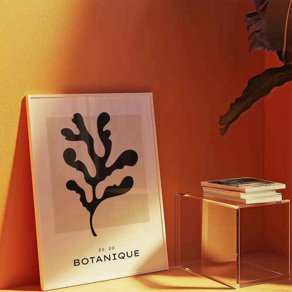 Modern botanical print poster featuring a black leaf design, framed and displayed against an orange wall with decorative elements.