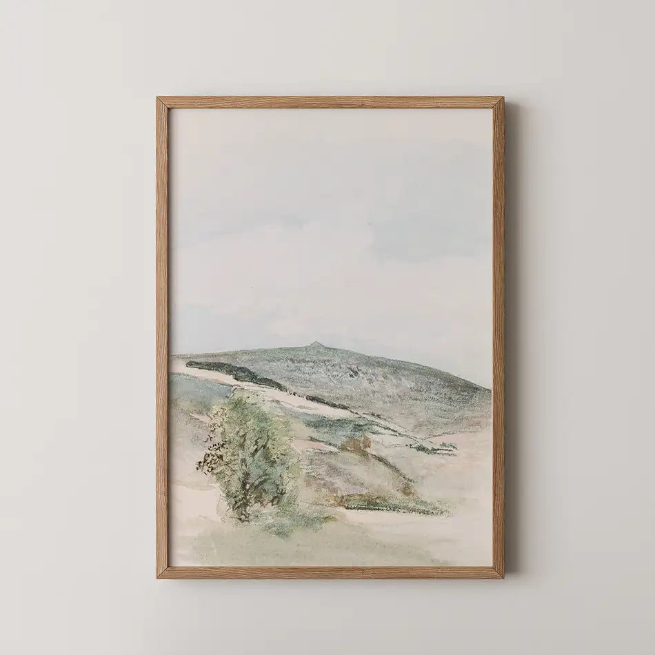 Framed painting of a serene landscape featuring rolling hills and a cloudy sky.