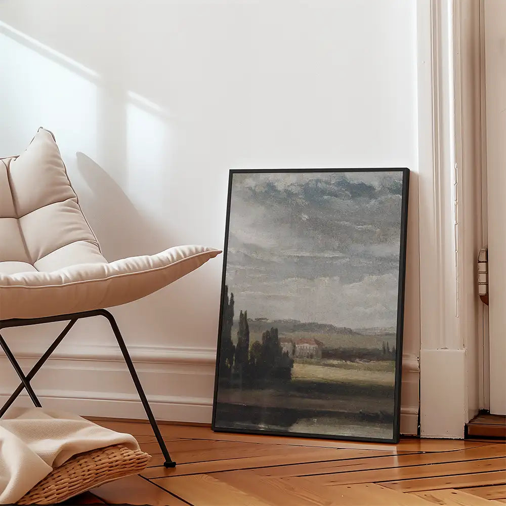 Framed landscape painting leaning against a wall next to a modern chair in a stylish interior setting.