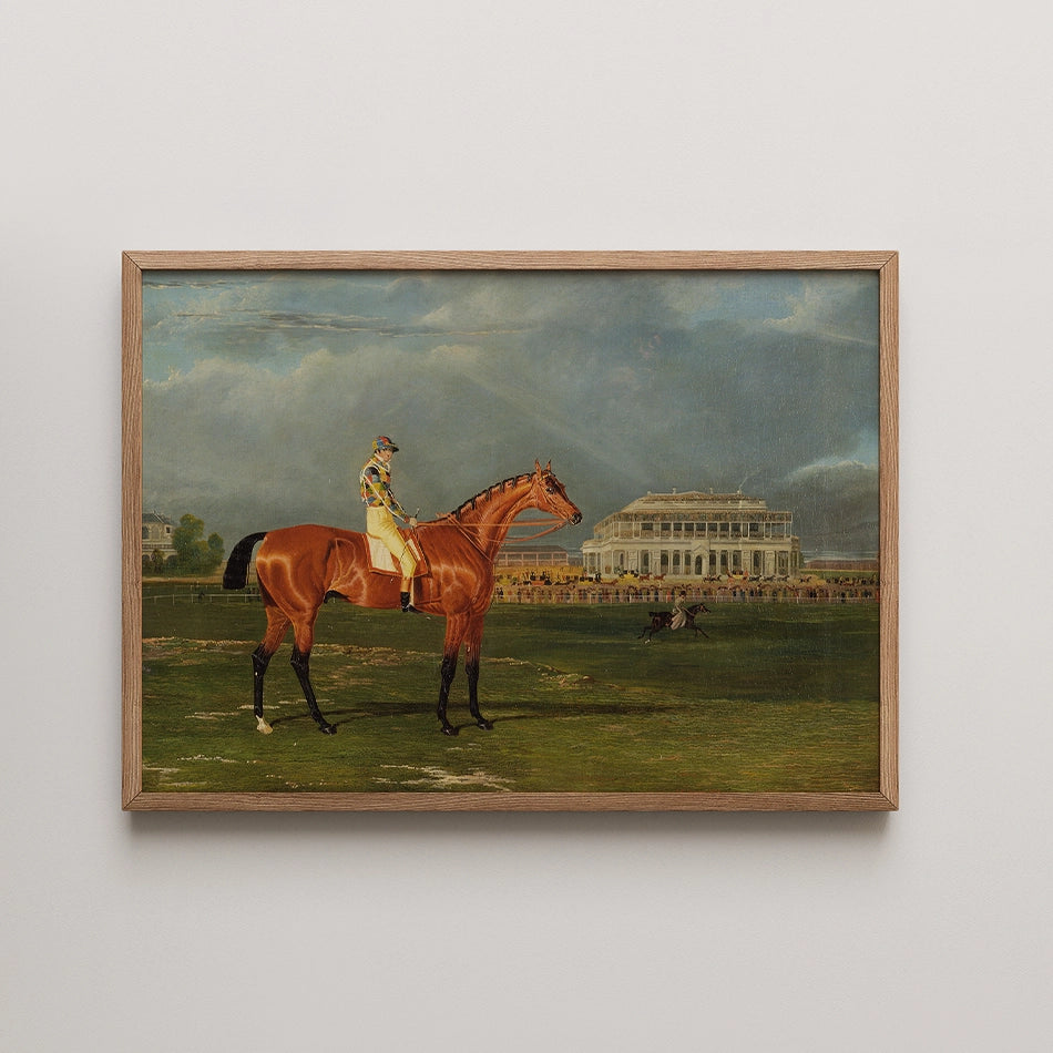 Framed painting of a racehorse with a jockey standing in front of a grand building under a cloudy sky.