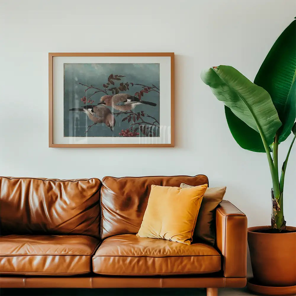 Framed painting of two birds perched on branches with red leaves, displayed above a brown leather sofa with a yellow cushion and a large green plant beside it.